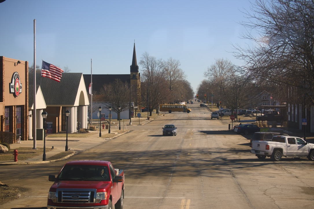 在Amtrak由Champaign前往Chicago Union路途上经过的美国小镇街景。时值美国前总统去世，全美执行降半旗。画面中充满了美国元素：皮卡、美式房子、美国国旗、美式校车等。
